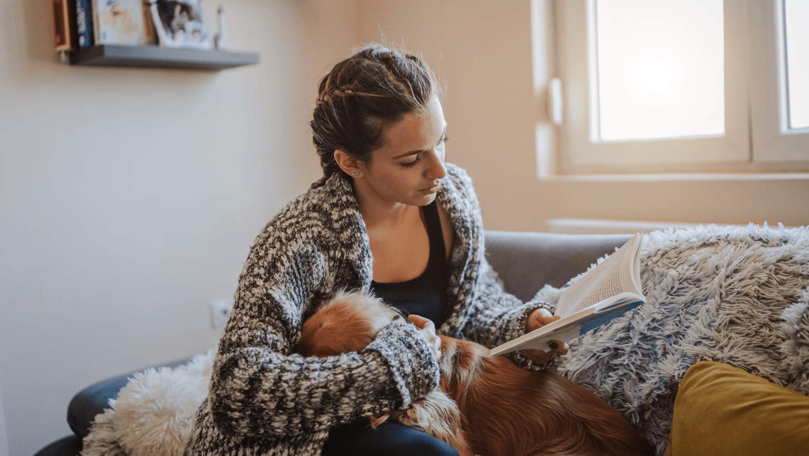 A lady going about her day, reading a book with her dog by her side.