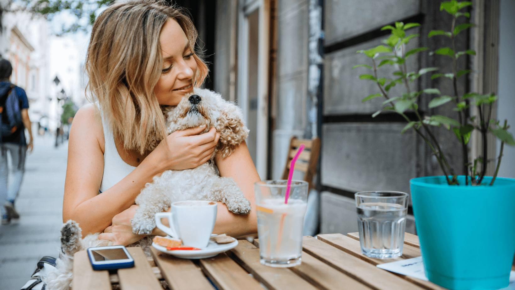 Joyful woman enjoying a café outing with her adorable dog, both smiling at a pet-friendly establishment in Queensland, Australia.